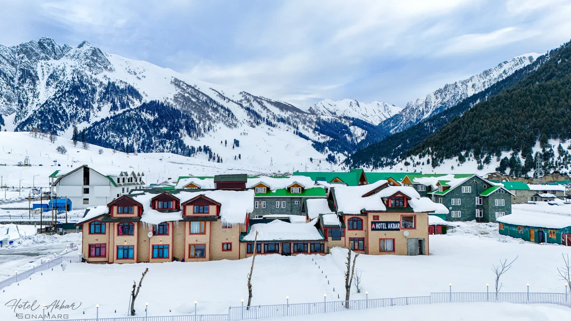 Alpine hotel amidst snowy mountain range.